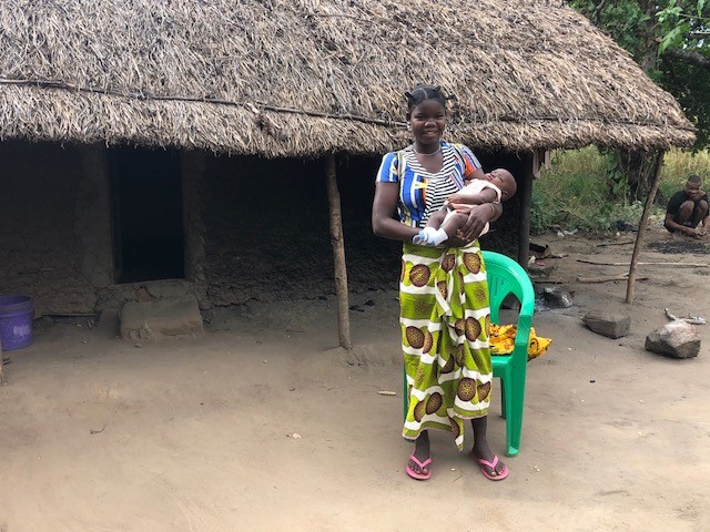 Diolista holds her healthy baby boy after a safe pregnancy, thanks in part to the three recommended doses of SP received from her TIPTOP community health worker (Credit: André Lamina / Jhpiego).